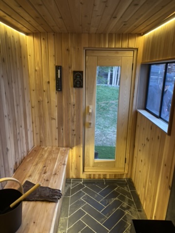 Cedar-lined sauna interior with bench, glass door and window