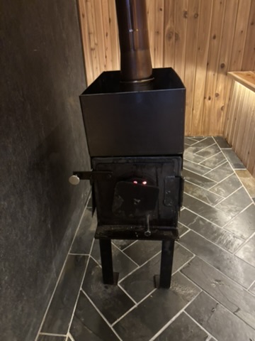 Wood-burning sauna stove glowing inside the trailer